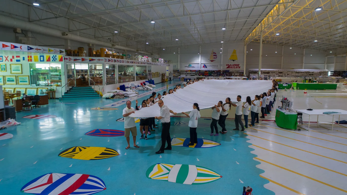The Rolly Tasker team holding a sail inside the Phuket loft